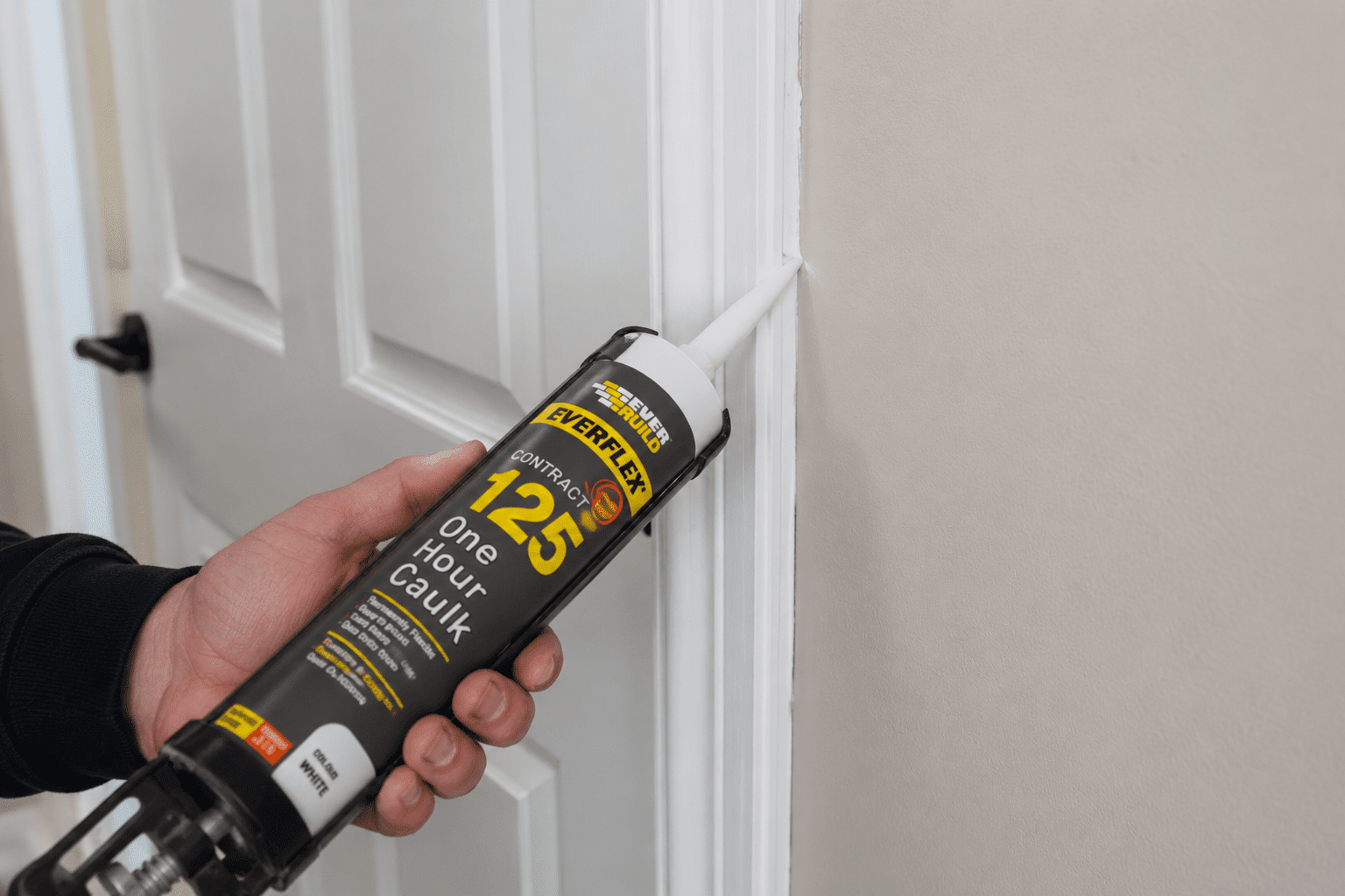 Caulk being applied by a decorator to seal the crack between a door frame and a wall prior to painting Orion Trade Supplies Rochester and Peckham 0001
